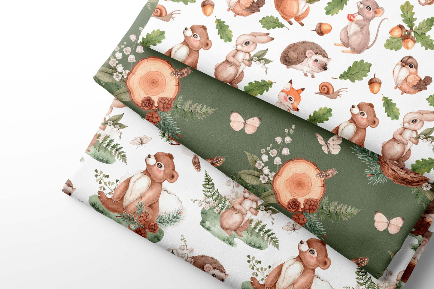 Three sheets of coordintaing fabric with woodland animal patterns on a white and green background