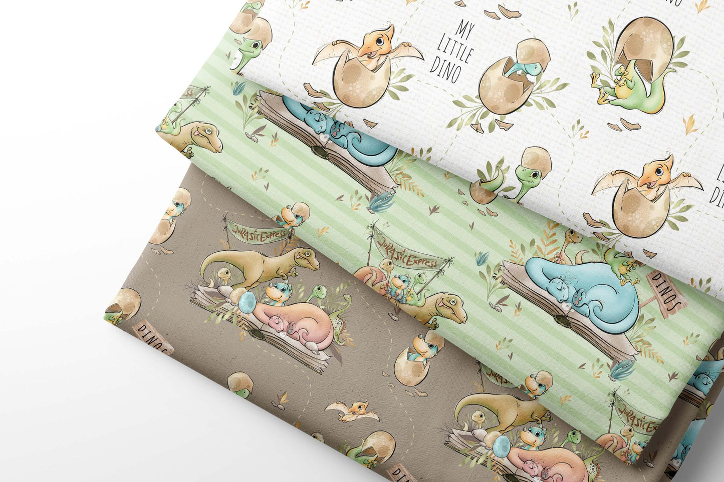 Set of coordinating fabric sheets with cartoon dino patter designs on a light green and brown background