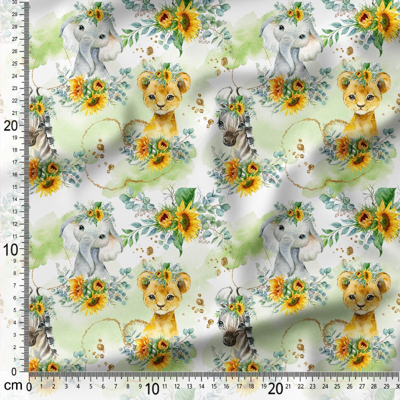 Fabric with lion cubs, elephants, and sunflowers on a white background with a ruler for scale.