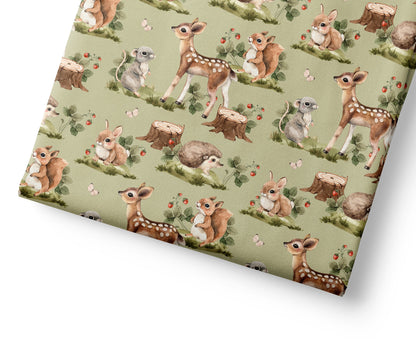 Woodland coordinating fabric with a pattern of deer and nature elements on a green background