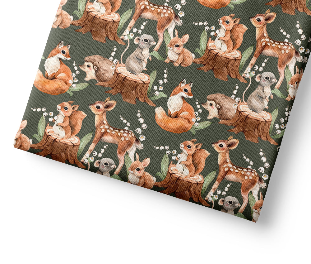 Patterned fabric with forest animals including deer, foxes, and squirrels on a green background.