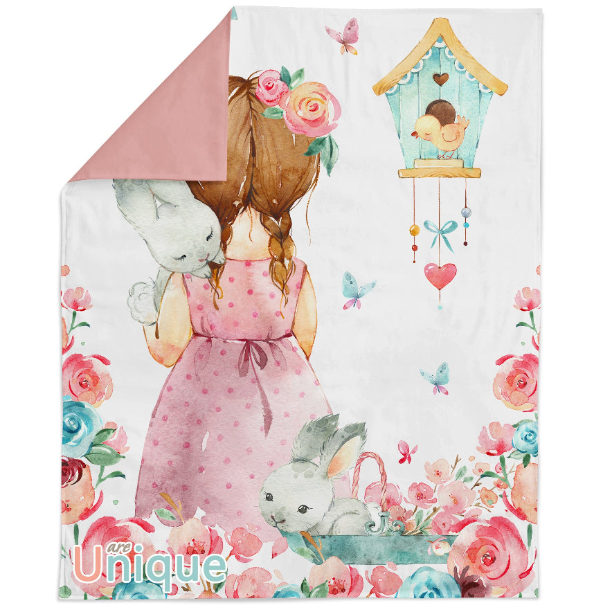A fabric panel featuring an illustration of a girl holding a bunny, with a floral background and a birdhouse