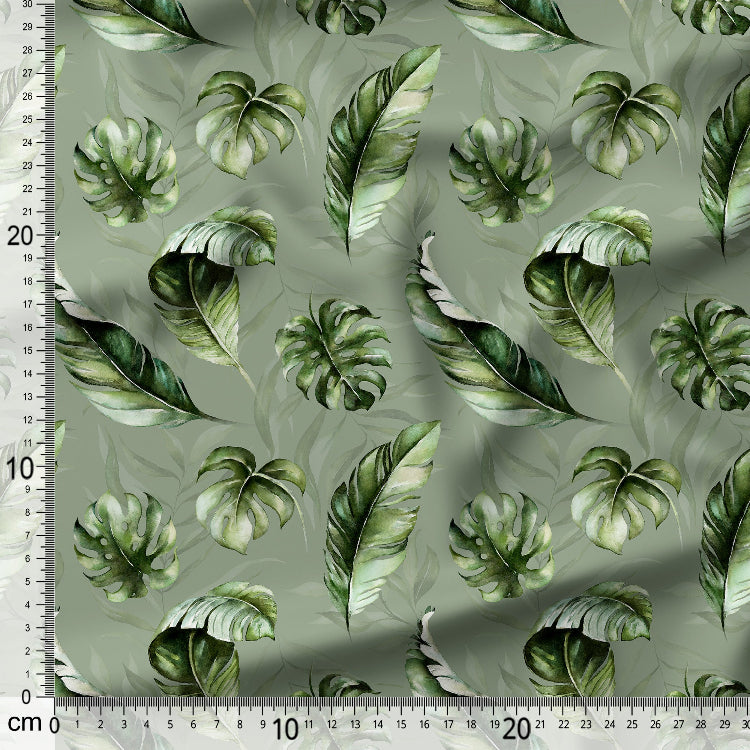 Fabric with green leaf pattern on a light gray background, measured with a ruler.