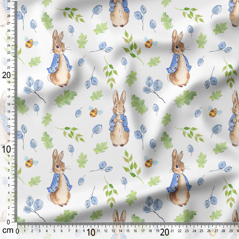 Fabric with cartoon bunnies and leaves pattern on a white background, measured with a ruler.