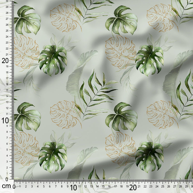 Fabric with green and gold leaf pattern on a white background, measured against a ruler.
