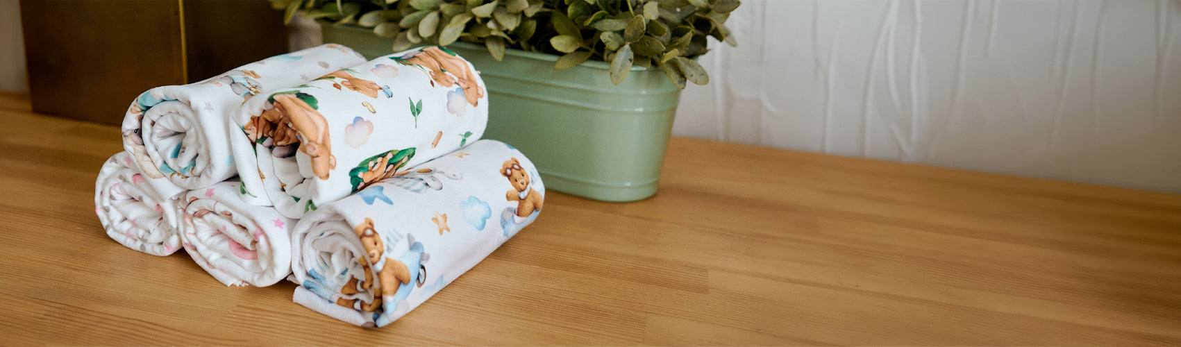 Stack of floral-patterned towels on a wooden surface with a plant in the background