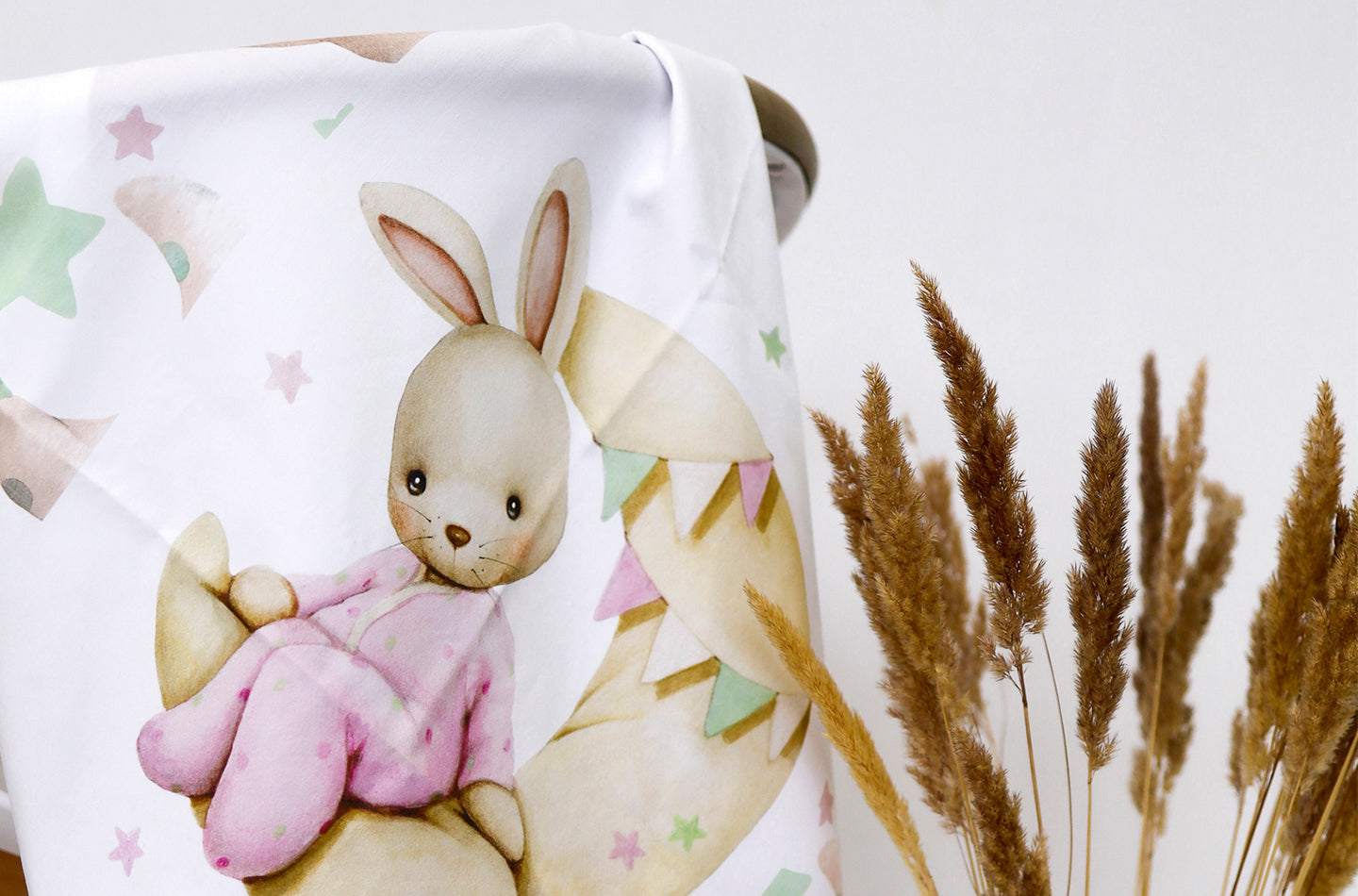 Fabric with a bunny design and dried plants on a white background