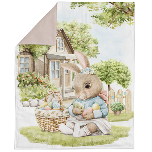 A fabric panel featuring an illustrated Easter rabbit family, including a rabbit with a basket of colorful eggs, set against a natural background with a house and trees.