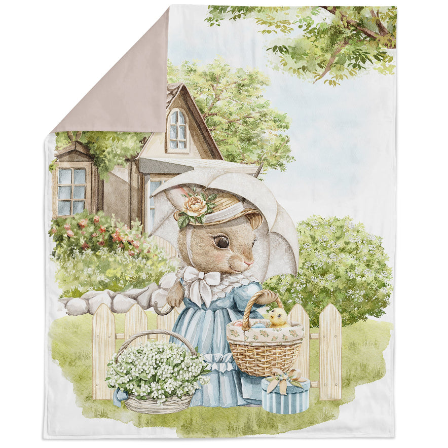 A fabric panel featuring an illustration of an Easter rabbit family, with the rabbit holding a basket of flowers, set against a rural house and tree background.